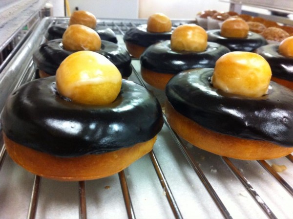 A glazed chocolate donut with a donut hole on top