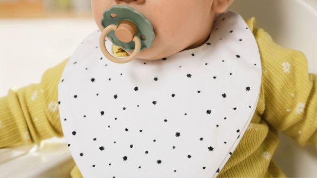 a baby drooling in a bib who is probably getting a drool rash