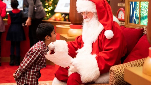 a kid stands in front of Santa during Santa pictures
