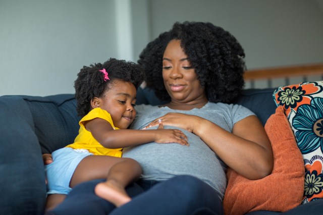 A daughter touches her mother's pregnant belly as they discuss how to tell the gender of the baby