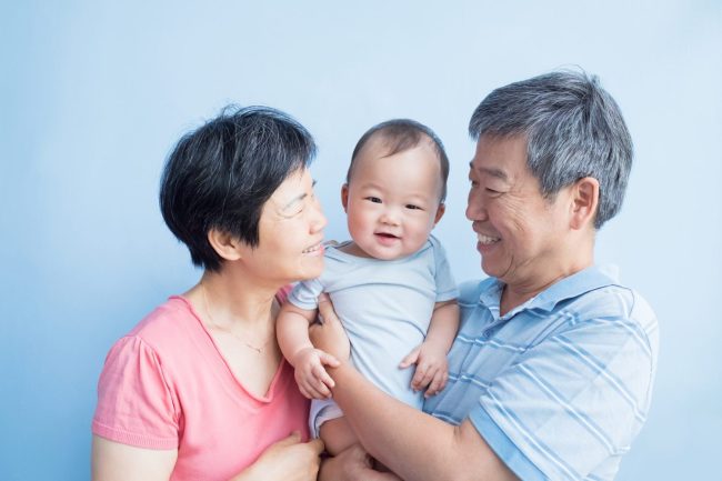 grandmother and grandfather holding infant between them