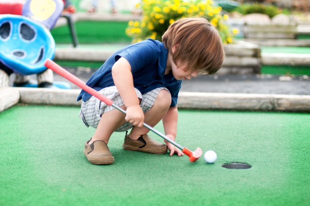 a kid plays mini golf