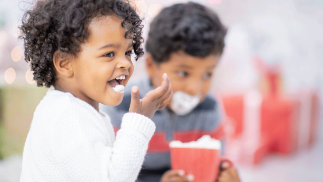 Two children enjoy hot chocolate with whipped cream at a hot chocolate spot in Dallas