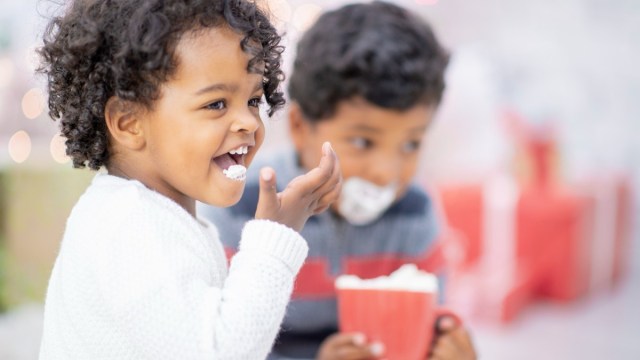 two kids sit drinking hot cholocate seattle with in red cups with whip cream