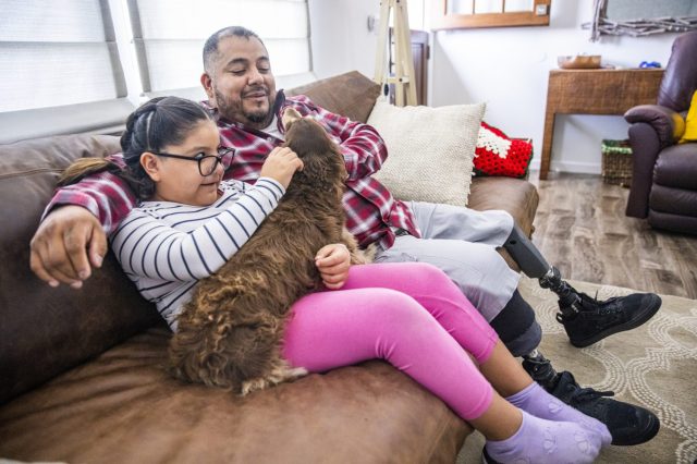 A Latinx family cuddles with their dog on the couch