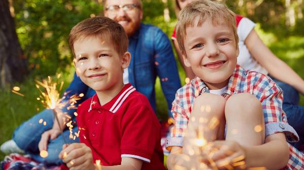 Two boys hold sparkler fireworks at a July 4th parade