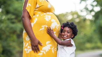 a pregnant mom dressed in a yellow flowered dress on her way to a baby sprinkle shower