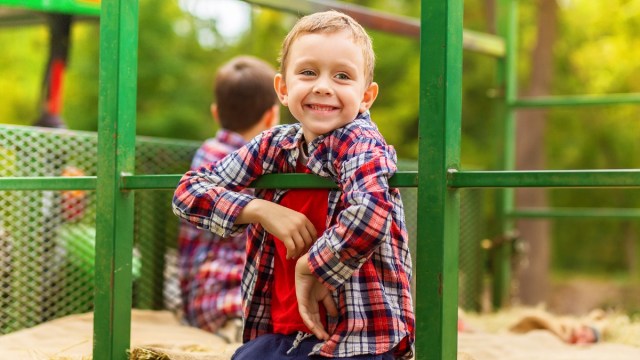 a boy smiles on green wagon while going for a hayride