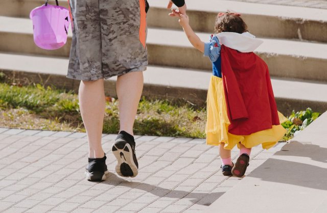 kid in Halloween costume holding parent's hand