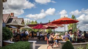 families sitting under orange umbrellas on the patio of King's Estate Winery in Oregon.
