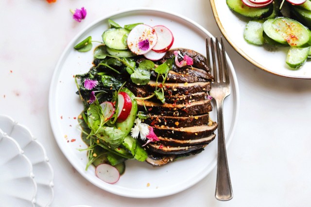 Sliced portobello mushroom "steaks" sit on a white plate as a finished plant-based Thanksgiving recipe