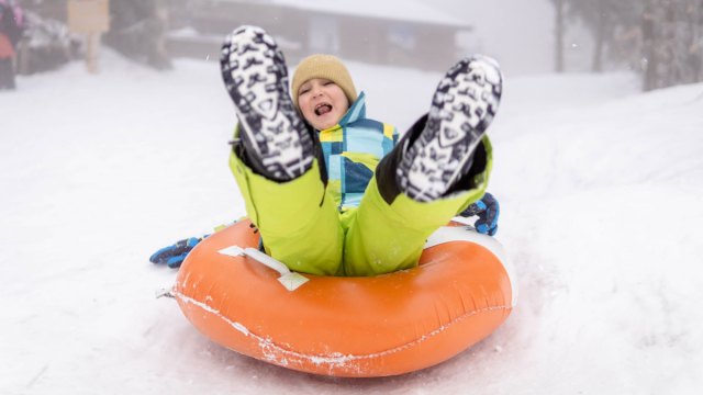 kid snowtubing on snowy hill
