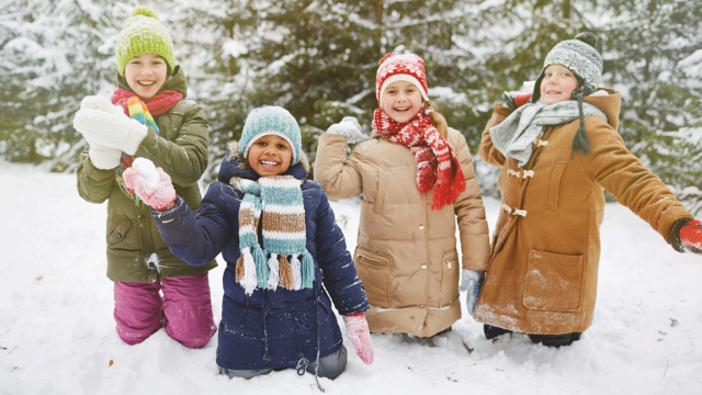 Four children in winter wear kneel in the snow about to throw snowballs at a place to play in the snow near LA