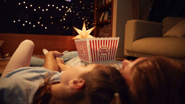 Father And Daughter Enjoying Movie Night At Home Together