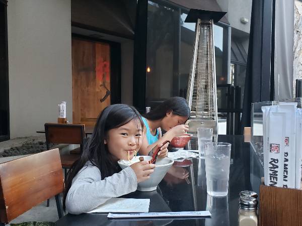 Two girls slurp ramen noodles