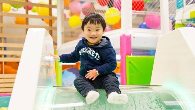 a kid sits at the stop of the slide smiling at this indoor kids birthday party seattle location