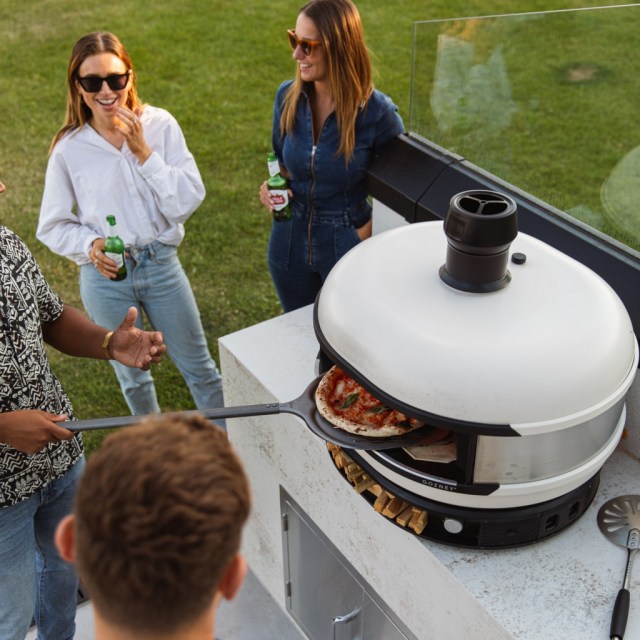 people gathered around the pizza oven outdoors