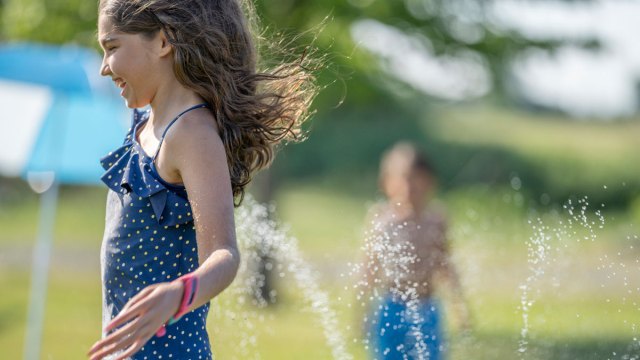 girl having summer fun in the sprinklers