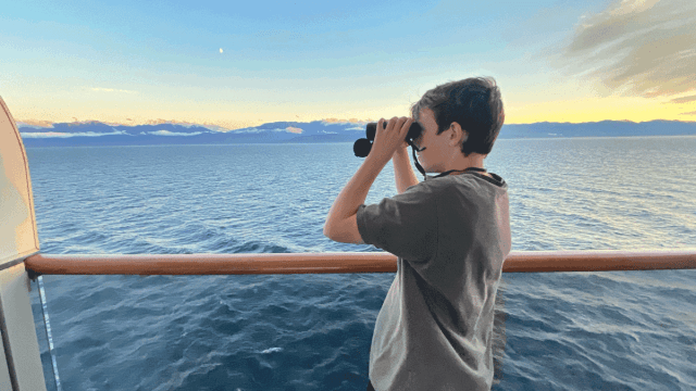 teen looking through binoculars on holland america alaska cruise