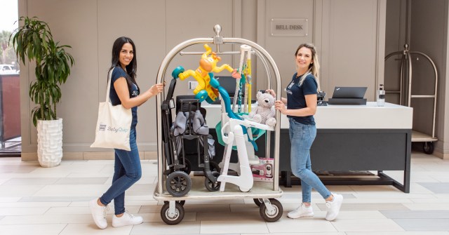 Two woman with a luggage cart full of baby gear.