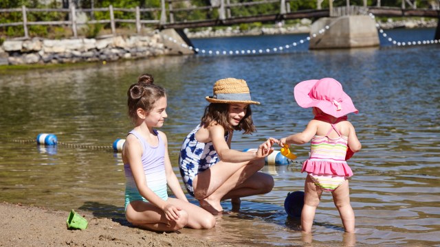 three little girls in colorful swimwear playing in the water