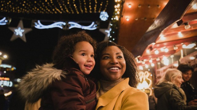 a mom and daughter stand outside a theater waiting to go see a christmas show in boston
