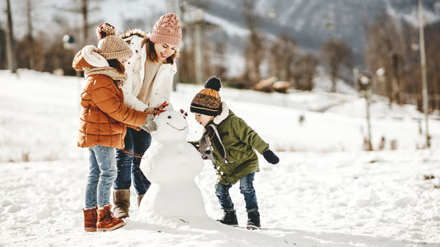 family making a snowman and laughing at Christmas jokes and snowman jokes