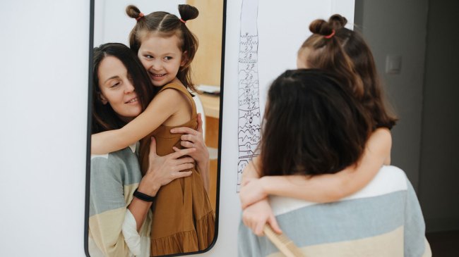 happy mom and daughter looking in the mirror