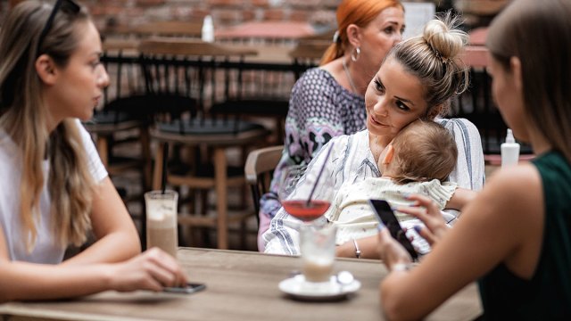 new mom holding baby and sitting with friends