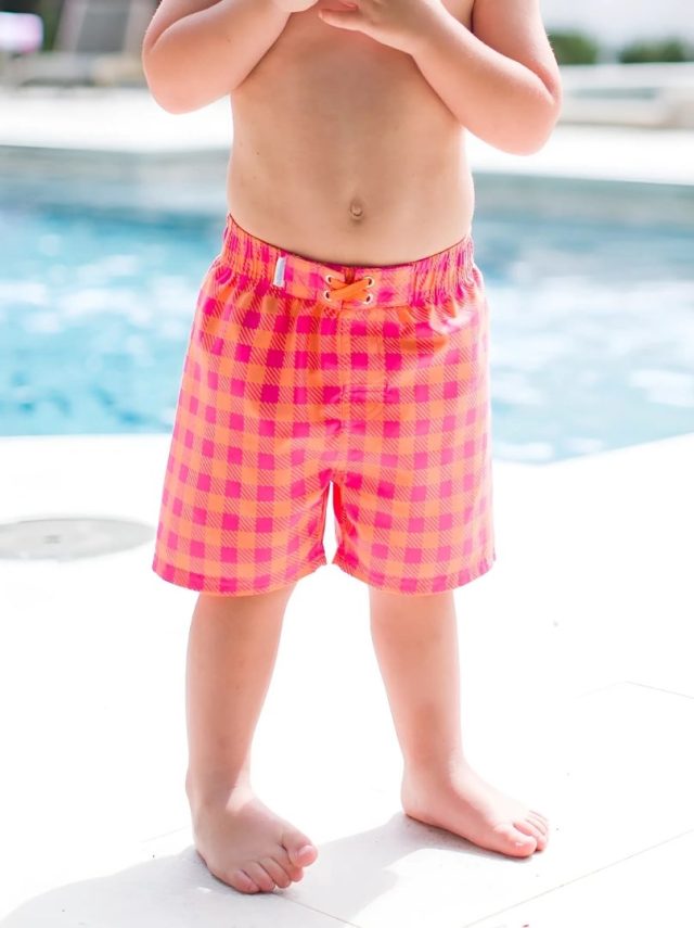 child wearing the checkered swim trunks by the pool