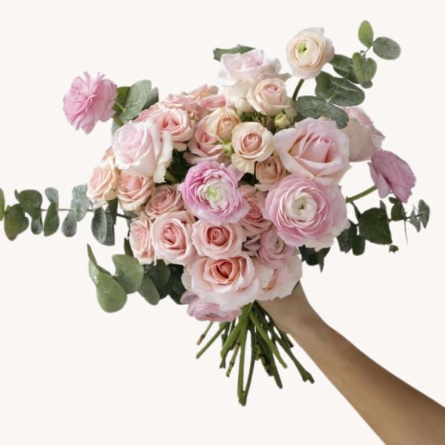 hand holding light pink tea rose bouquet