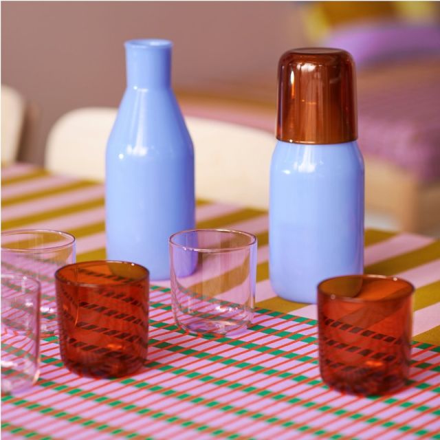 amber and lilac glasses next to two light blue carafes