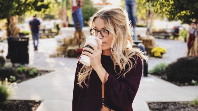 woman sipping coffee walking in a park