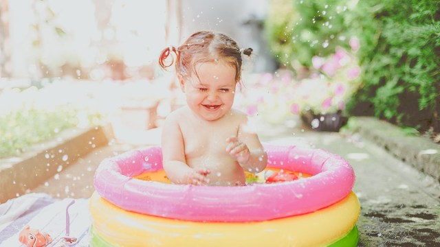 a baby splashing in a kiddie pool for outdoor water play activities