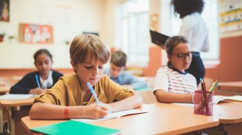 boy sitting as his desk in class