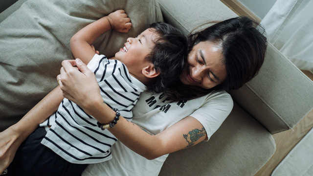 mom and toddler playing a game while lying down