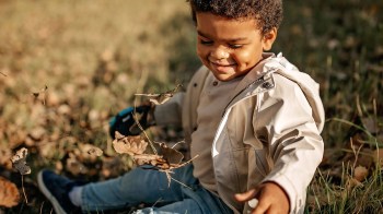 happy toddler playing in the grass for a story on letting happy kids be happy