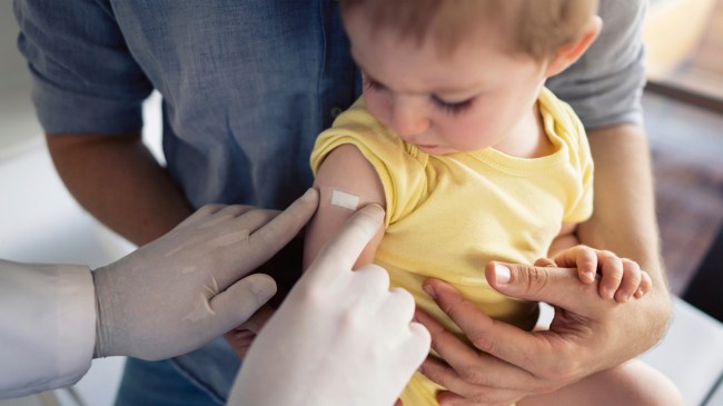 a baby getting their arm bandaged after having a vaccination like the new rsv vaccine