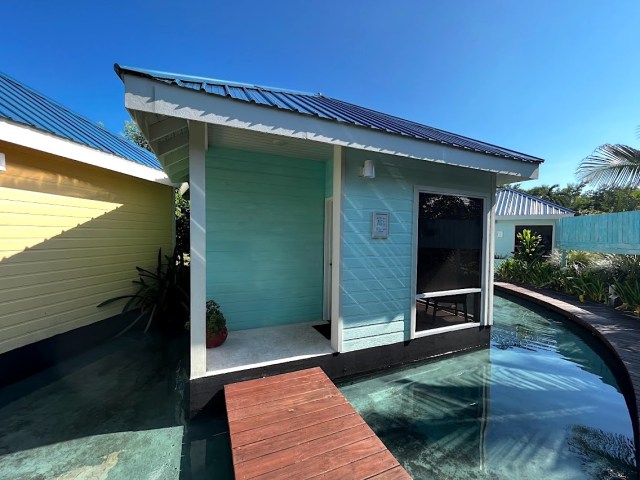 Blue private massage room with wood walkway leading up and water surrounding. 