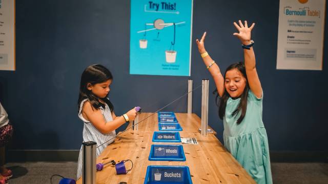 girl with hands in the air celebrating a successful experiment at Orlando Science Center