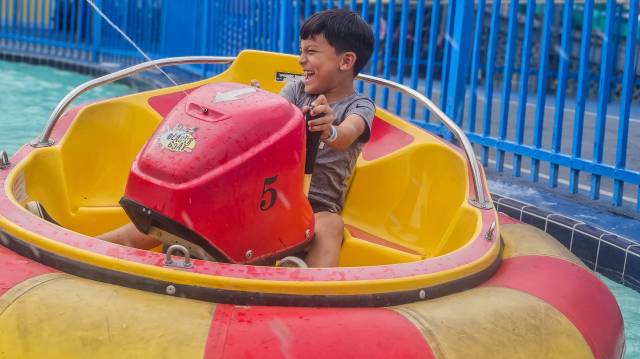 smiling boy spraying water gun on bumper boat at Fun Spot America in Orlando, Florida