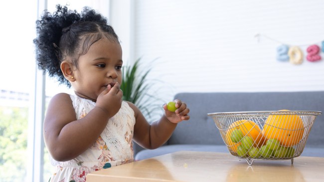 a toddler about to eat a whole grape, which is a choking hazard for toddlers