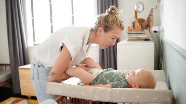 a mom after changing her baby's diaper hopefully using the best diaper rash treatment