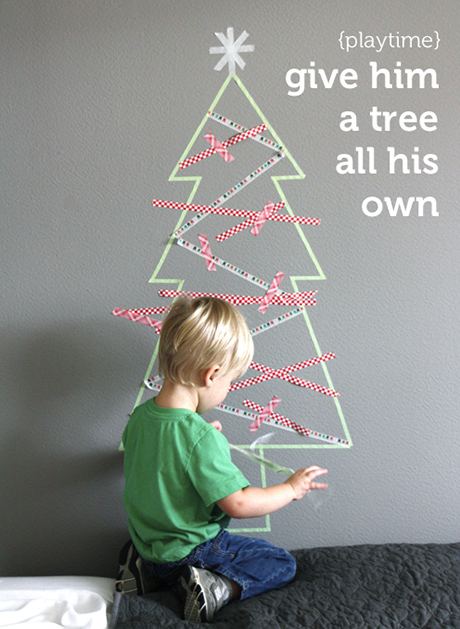 a toddler decorating a washi tape tree outline as an example of a toddler-proof christmas tree