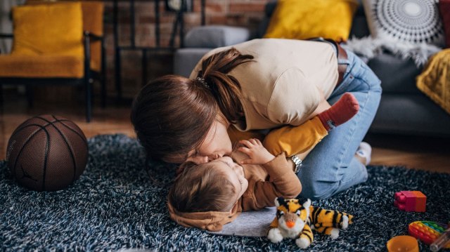 mom kissing her toddler on the floor