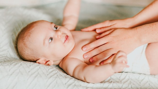 an infant receiving a baby massage from their mom and looking like they're really loving it