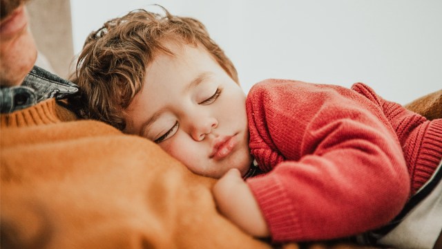 a little boy dozing on his dad for a story answering 'is melatonin safe for kids?'