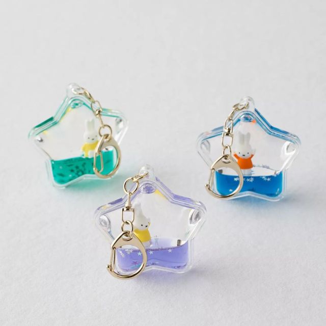 three star-shaped keychains filled with colorful sparkles and a tiny bunny figure