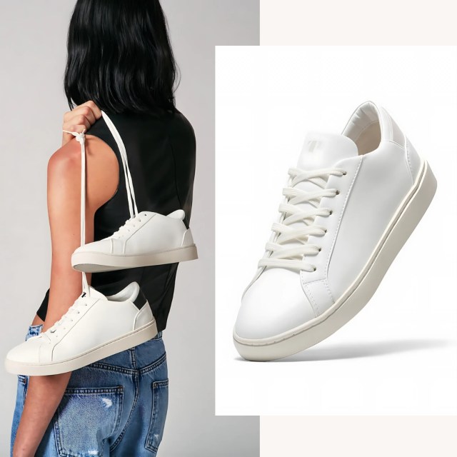 person holding the sneakers over their shoulder by the laces