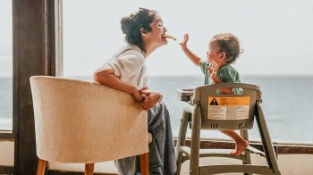a baby feeding their mom a piece of food for a story on weird things parents do